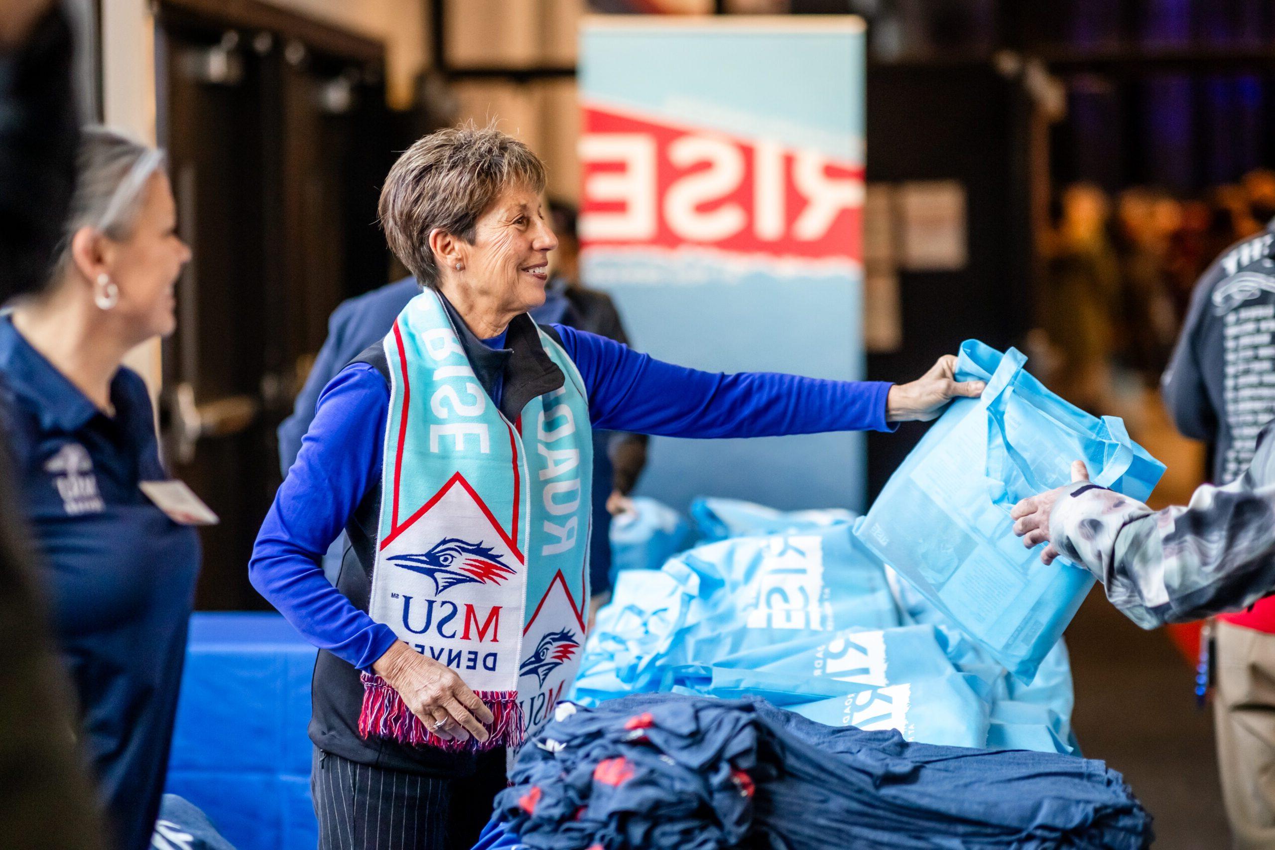 Passing out MSU Denver scarves at Roadrunners Rise Campaign Launch event